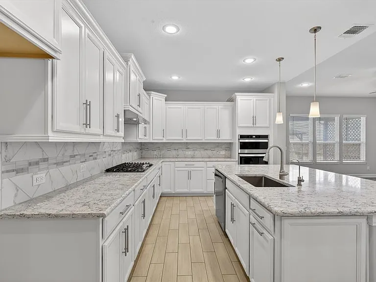 Spacious kitchen featuring extensive white cabinetry, light-toned countertops, and a full tile backsplash