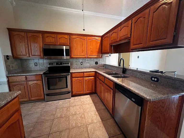 Kitchen - Featuring stainless steel appliances, granite countertops & tiled flooring.