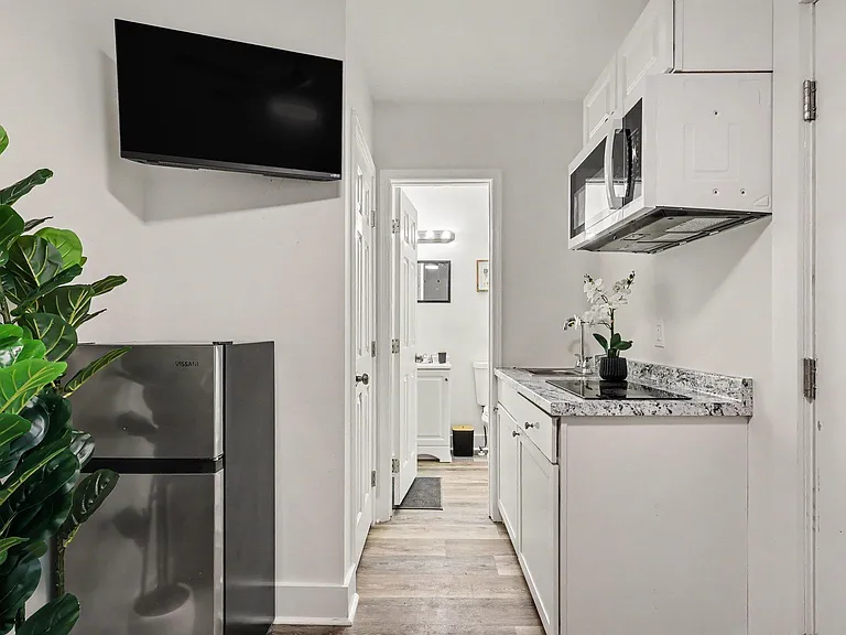 Efficient kitchenette with stone-look counters, sink, and microwave, plus mini fridge for convenient everyday meals.