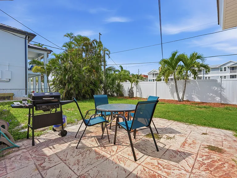 Fenced backyard includes patio off kitchen with gas grill, table/chairs and fire pit.