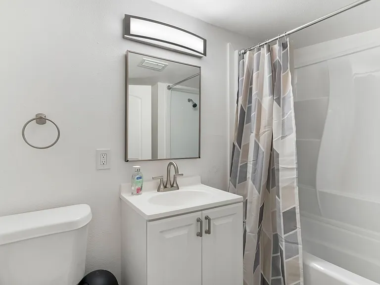Clean full bath with a single-sink vanity, framed mirror, and a shower/tub combo with curtain for easy daily use.