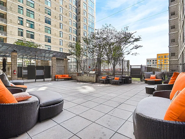 an outdoor patio with chairs and tables and a building in the background