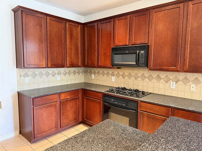 Spacious kitchen with gas cooktop and granite countertops.