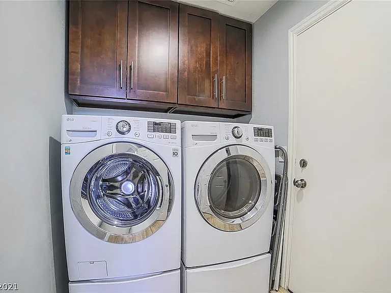 Laundry room. Front load LG washer and dryer on pedestals with storage.