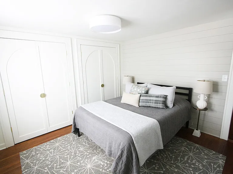 The second floor bedroom features a queen bed and soft bedding, a floor length mirror, large double closet with hangers, and a luggage rack.