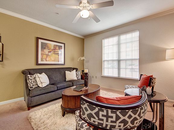 A cozy living room with a wide window overlooking the property and ceiling fan