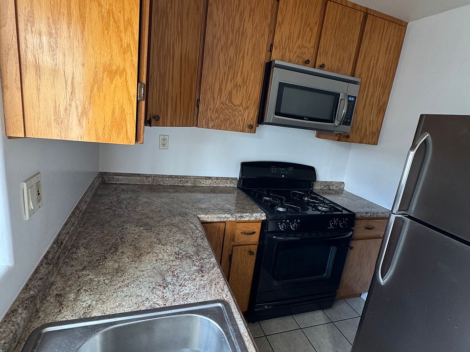 Custom kitchen cabinet with microwave hood, stove, and fridge, porcelain tiles in the kitchen.