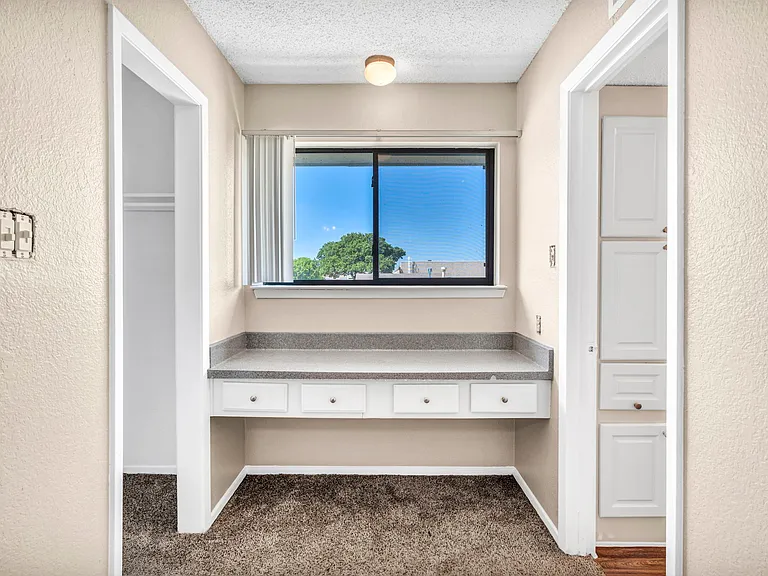 Vanity area with built-in counter and lighting for added convenience.