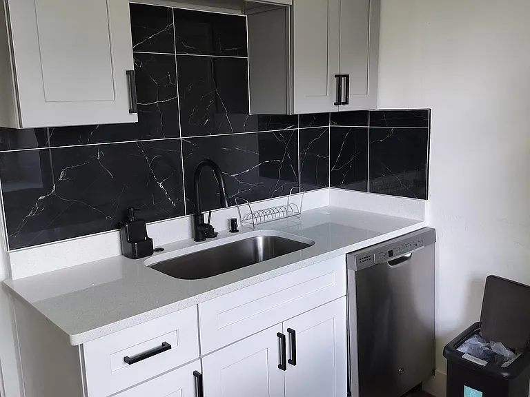 Updated kitchen area with shaker cabinetry, deep sink, quartz-style counters, and a sleek tile backsplash.