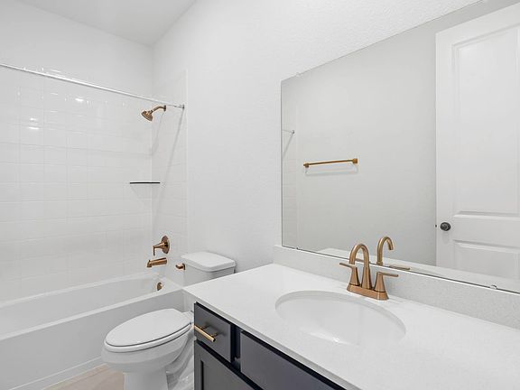 Modern bath with a large vanity featuring sleek navy cabinetry with brass handles and fixtures, and