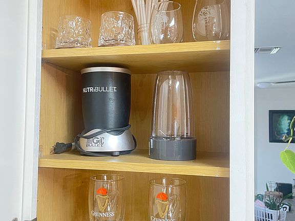 A bullet for making shakes and dressings, whiskey glasses, wine glasses, and beer mugs are in the fridge.