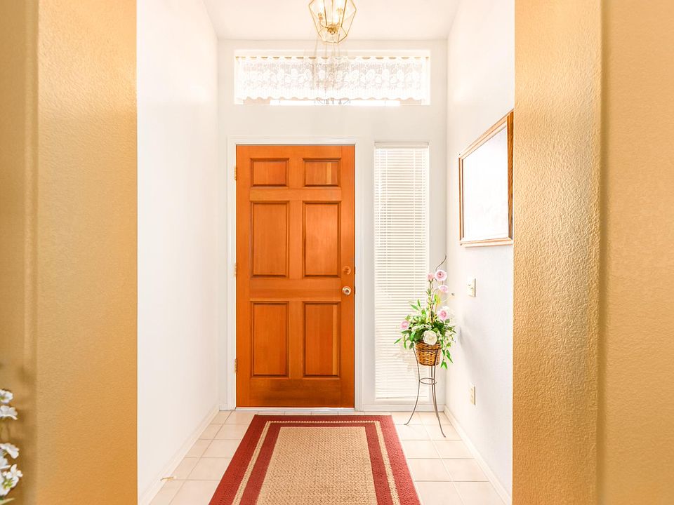 Large hardwood door makes for an attractive, secure entrance with large windows above and next to the door providing a cheery, well lit entrance with privacy vertical blinds next to the door.