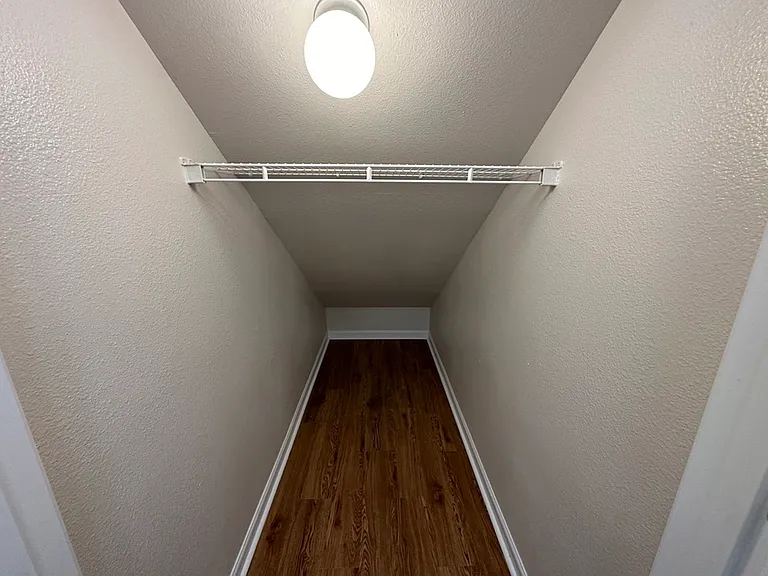 Cozy walk-in closet with elegant wood-style flooring and bright lighting. Cozy walk-in closet with elegant wood-style flooring and bright lighting.