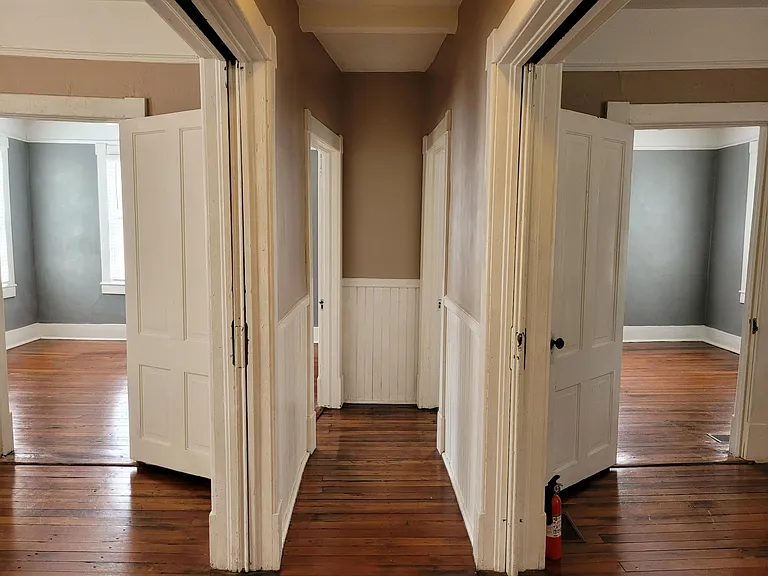 Central Hall - Living & Dining divided by double pocket doors. Bedrooms ahead through doors. Decorative fireplace, hardwood floors, high ceilings, plaster walls with picture molding, & ceiling fan with light in each - living, dining, & both bedrooms.