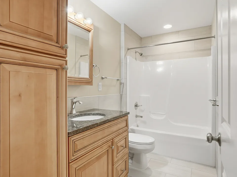 Deluxe well lit bathroom with ceramic tile flooring, granite top vanity , and upgraded fixtures