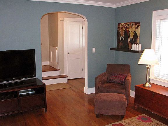 Living room with hardwood floors, arched doorways, and crown molding.