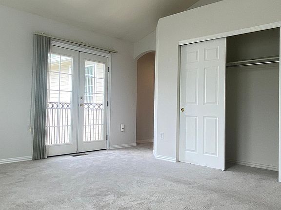 Master bedroom with one of two, large closets, ceiling fan, patio balcony doors.
