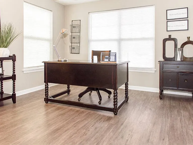 Second bedroom with plank flooring and large, bright windows being used as an office