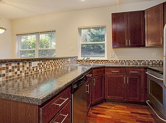 Cherry wood cabinets, wood floors, breakfast bar and tile back splash.