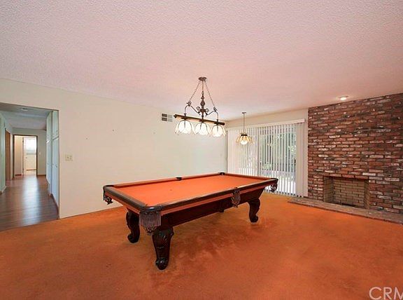 Living room with floor-to-ceiling brick fireplace, currently used as a game room