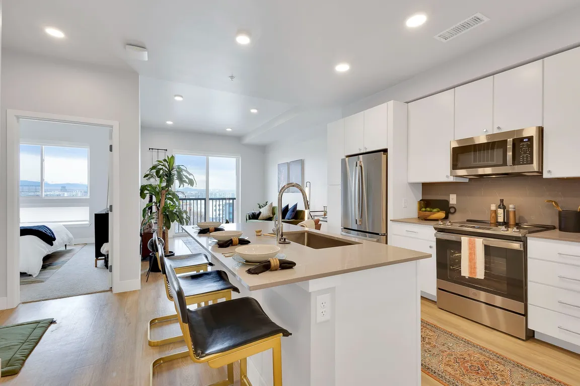 Modern kitchen with sleek white cabinets, stainless steel appliances, elegant countertops, and cozy bar seating.