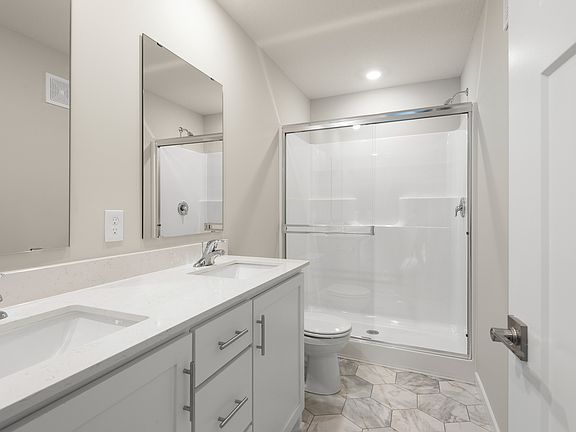 The master bathroom has dual sink vanity and step in shower.