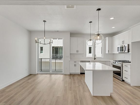 Modern kitchen with white cabinets, stainless steel appliances, an island, and pendant lighting. The