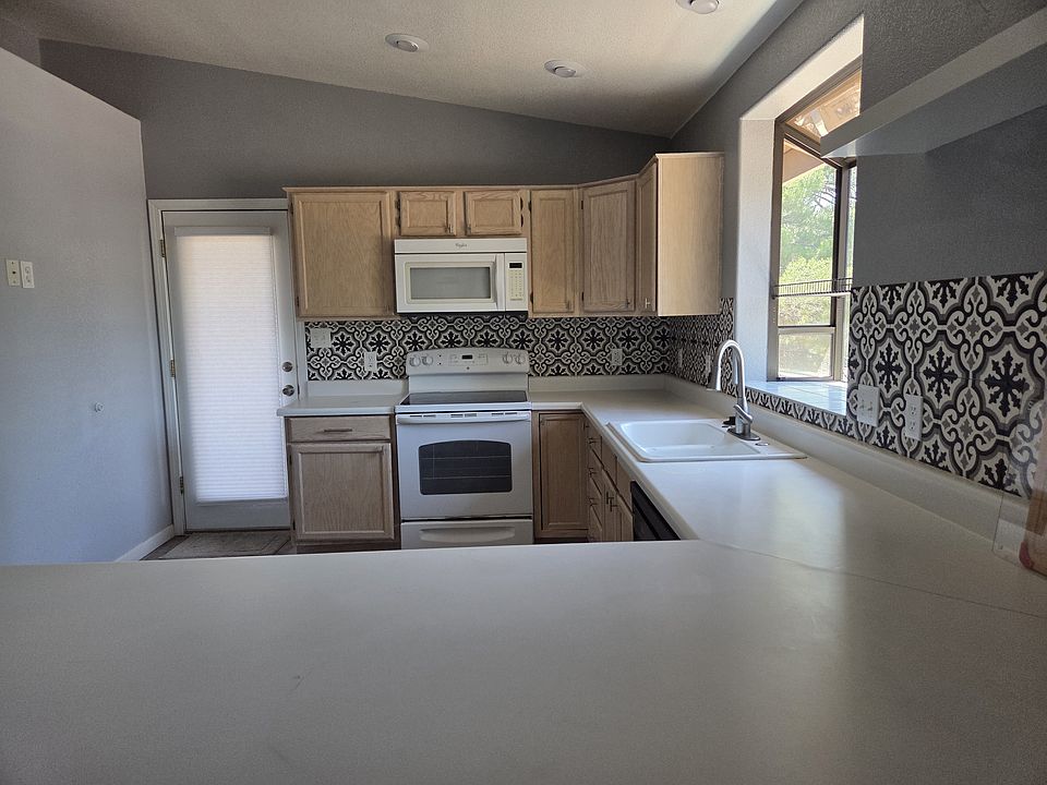 Large kitchen with lots of cabinets, dishwasher, door leading out to the shaded deck.