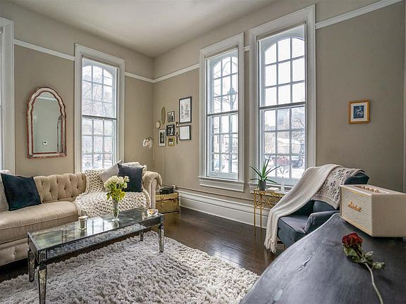 Great room living area with soaring ceilings, refurbished original hardwood floors, and nearly floor to ceiling windows