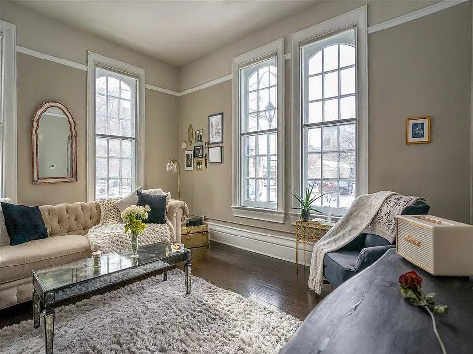 Great room living area with soaring ceilings, refurbished original hardwood floors, and nearly floor to ceiling windows