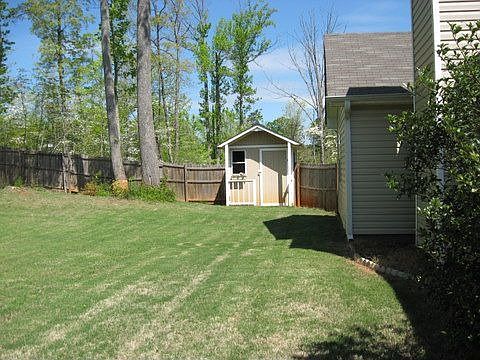 Fenced back yard has storage building