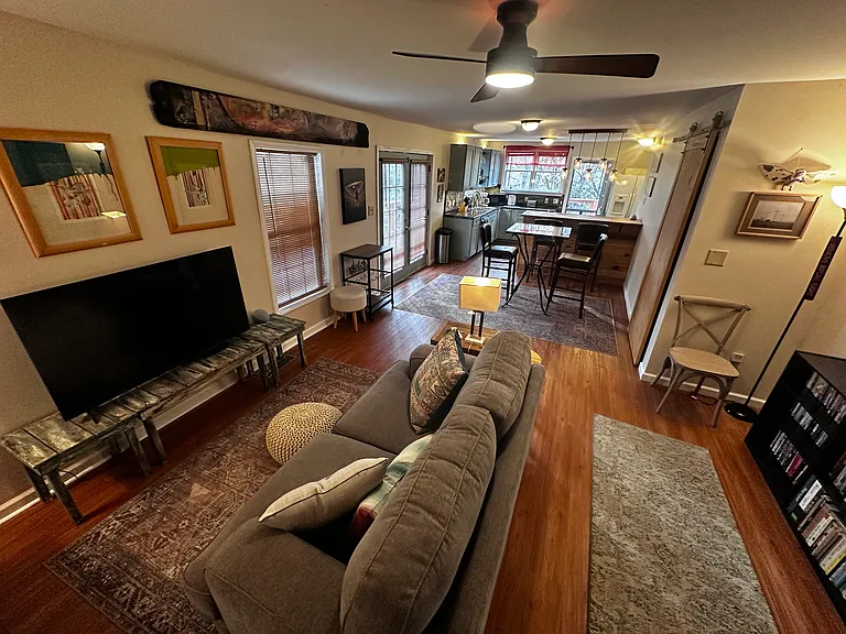 Open Living, dining, and kitchen with doors to deck at left and rear.