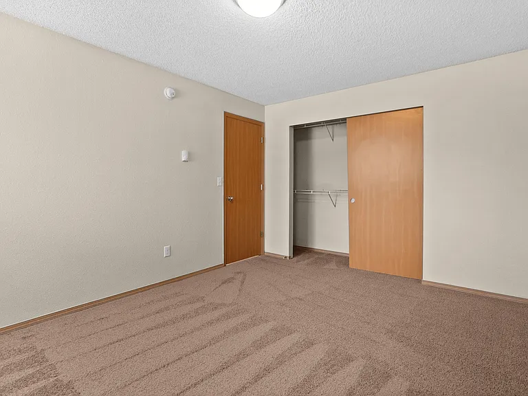 Cozy bedroom with plush carpeting and a spacious closet featuring sliding doors. Cozy bedroom with plush carpeting and a spacious closet featuring sliding doors.