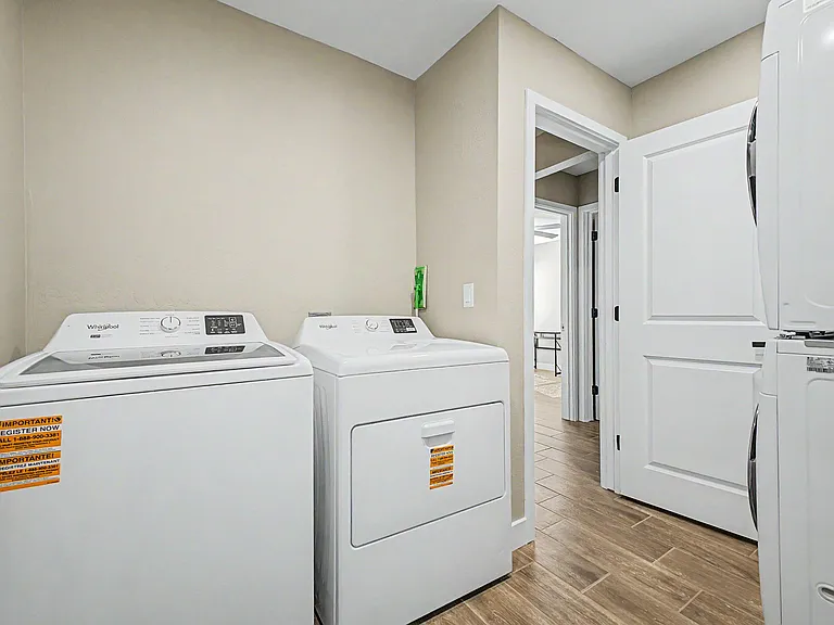 Dedicated laundry area with full-size washer and dryer and durable tile flooring, positioned near the main hallway for easy a