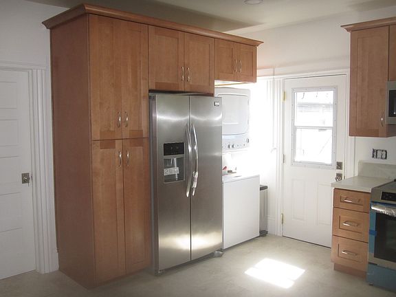 Kitchen view of pantry, fridge and washer/dryer + back door