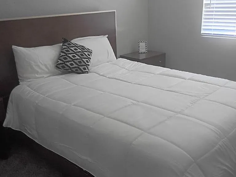 Comfortable bedroom with a full/queen bed, nightstand, and a window with blinds for light and privacy.