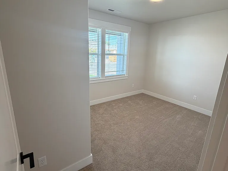 The cozy front bedroom is filled with natural light from its front-facing windows, creating a welcoming and comfortable space perfect for rest, work, or guests.