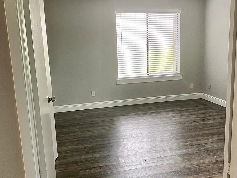 Large bedroom with double doors & wood blinds. Open to living space.