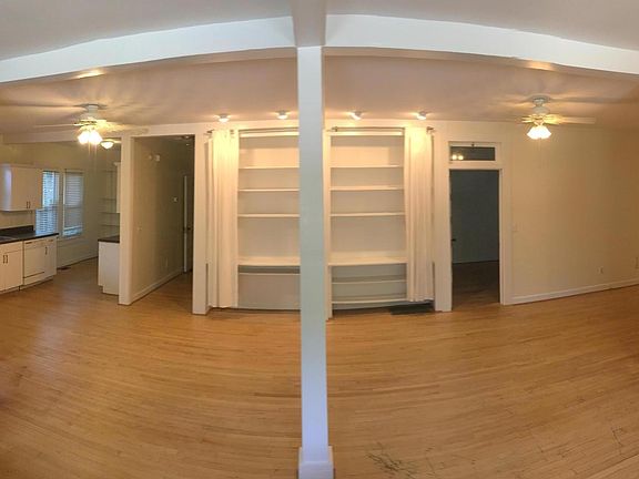 The duplex wall has been removed allowing for plenty of open space in the living area. Old chimneys remain in the space, showing exposed brick from two locations.
