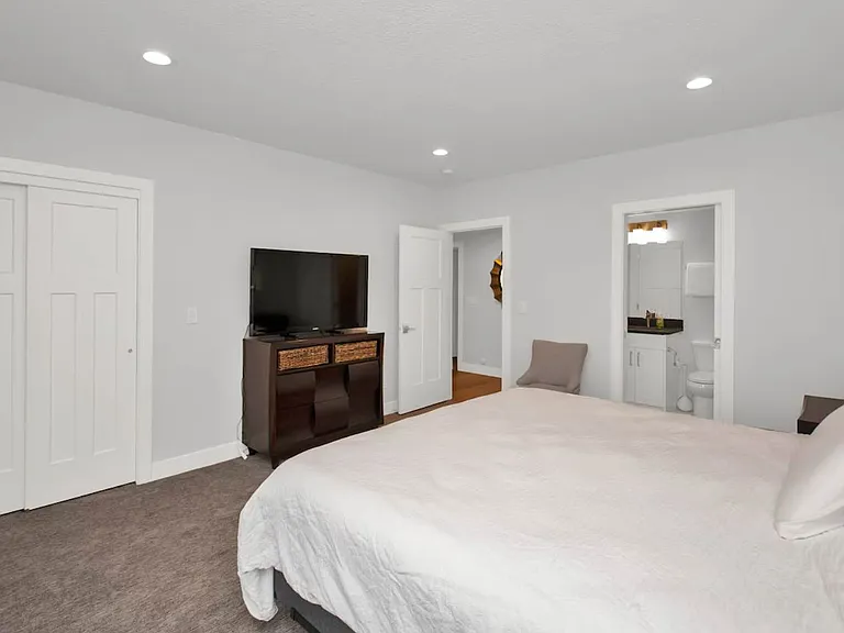 Bedroom with king sized bed, closet, smart tv, connected full sized bathroom and french doors to outside patio with gas fire pit and private hot tub (not pictured).