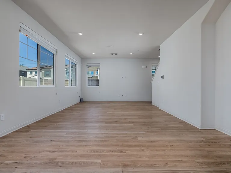 Another angle of the open living area showcasing bright natural light, sleek laminate flooring, and spacious layout_perfect for arranging dining and entertainment spaces with a modern, airy feel.