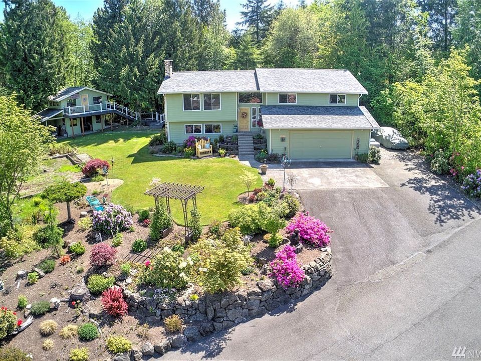 Welcome to Benson Hill and a hidden gem at the end of a private drive! This spacious home sits on a gorgeous shy acre lot, backing to a greenbelt and featuring a lush landscape. The incredible deck leads to a separate, adorable 2-story outbuilding. Offering the best of Northwest style, comfort, and abundant light, you'll be drawn to the warm and inviting living room that showcases a lovely Arizona Sandstone fireplace. The incredible kitchen has been recently remodeled with granite & stainless steel finishes, white cabinets and upgraded features that delight at every turn. You'll love the double ovens, pantry cabinets and buffet counter. The open-concept provides for easy entertaining and the large slider will draw you outside where you can extend your living and entertaining to the tranquil, expansive deck. This amazing feature is newly installed and connects to the 2-story outbuilding which features a deck of its own! 