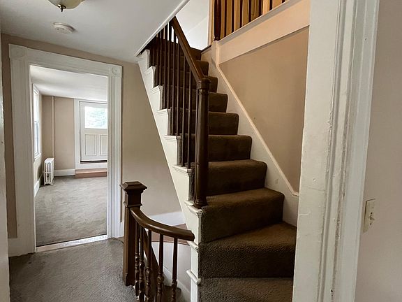 Hallway to the living room, stairs going up to 2 bedrooms, and winding stairs going down to the main entrance.