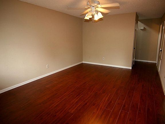 Formal living room with newly installed laminate wood flooring, fresh paint and large ceiling fan.