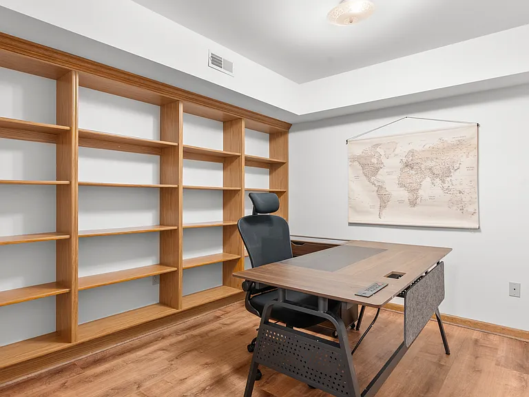 Dedicated basement office with a spacious desk, ergonomic chair, and extensive built-in shelving for a comfortable and organized workspace.