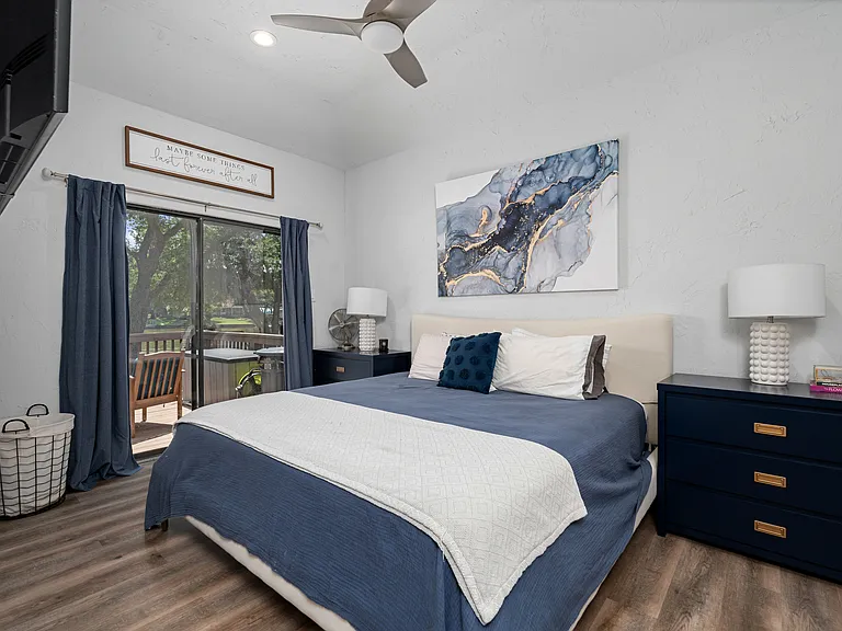Primary bedroom with king size bed with TV and glass sliding doors to outside patio area.