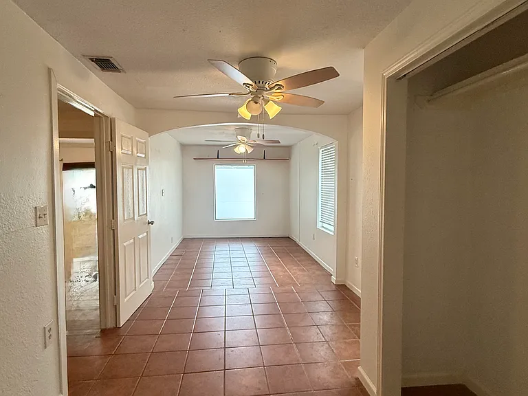 2nd BR "flex suite" -- photo taken in bathroom door looking down the entire bedroom. Front window looks out onto driveway and has a removable frosted coating on it for privacy. Closet visible on the right in photo. Open door on L leads to living room.