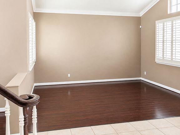 Open living area with rich wood flooring, plantation shutters, and natural light