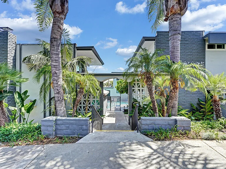 Front entrance of the apartments surrounded by palm trees.