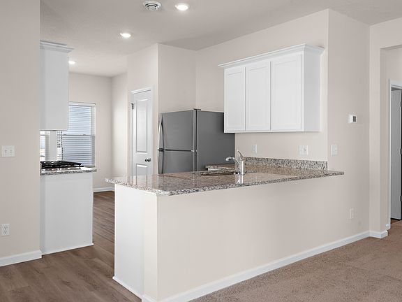 The kitchen has stainless steel appliances and plank flooring.